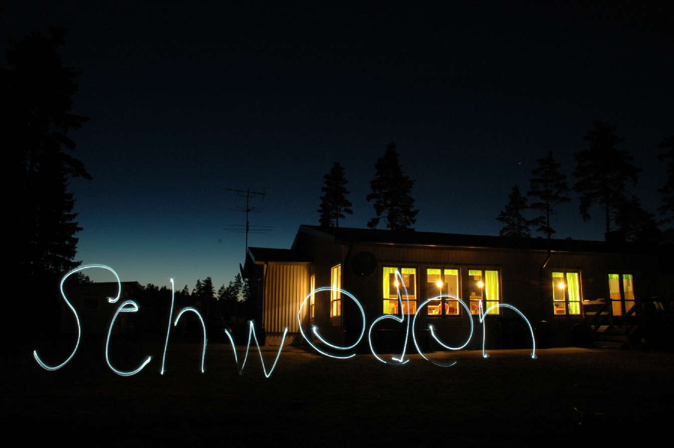 Gruppenhaus in Schweden bei Nacht mit leuchtendem Schwedenschriftzug